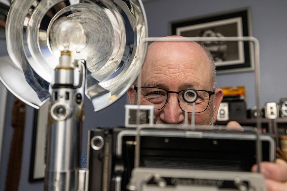 Professor holding old camera up to eye
