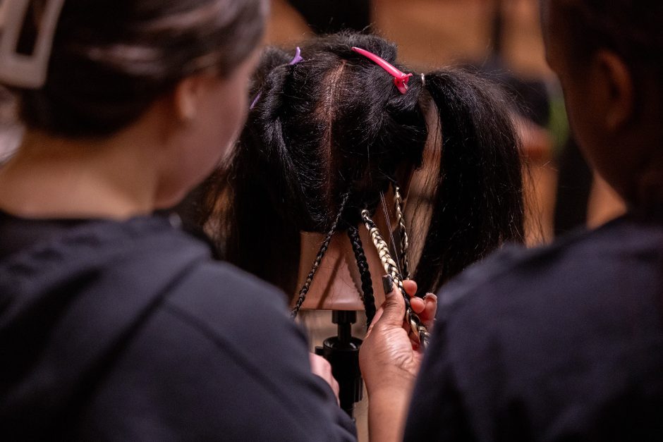 Student braiding a mannequin's hair