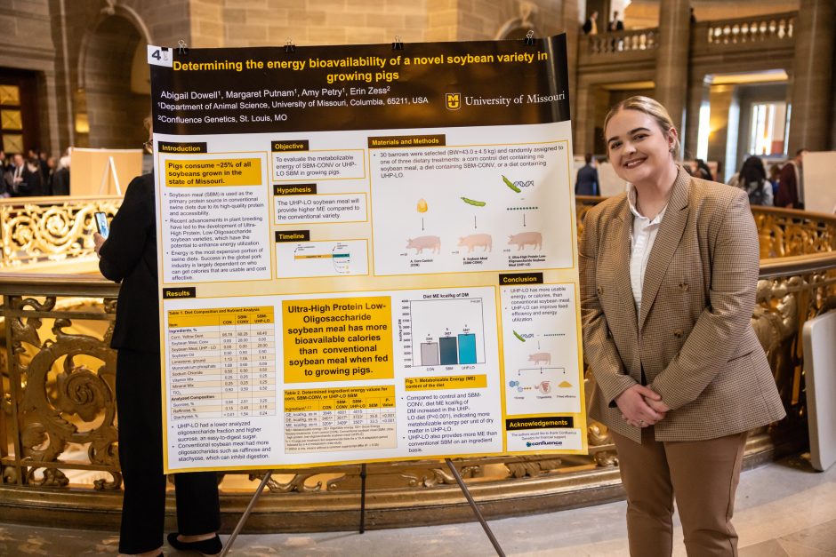 Student standing next to research poster