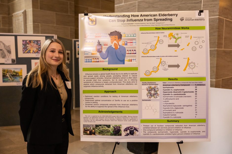 Student standing next to research poster