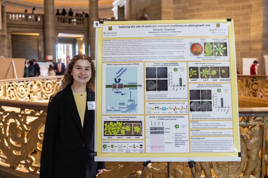 Student standing next to research poster