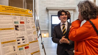Student discussing research poster with visitor