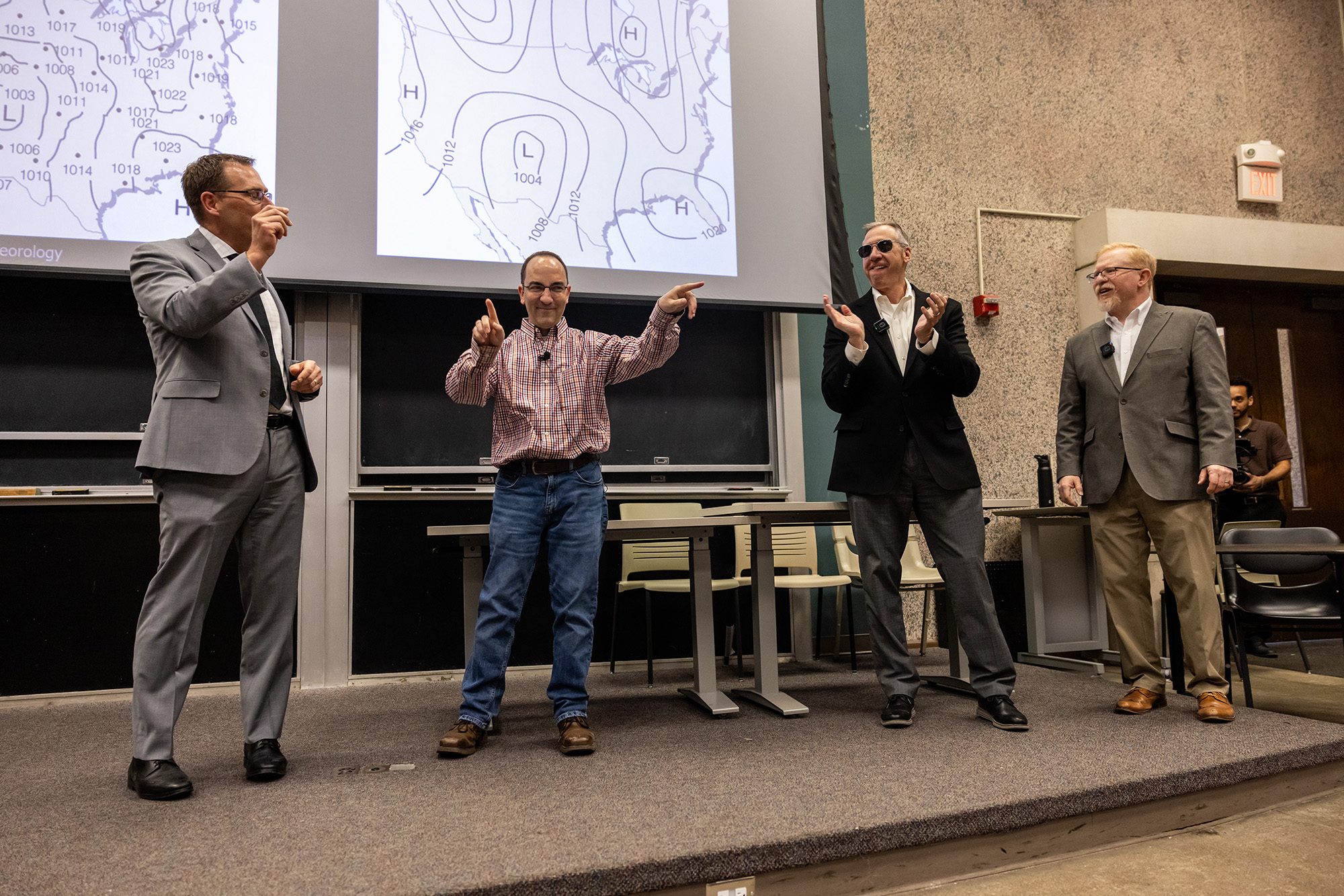 Four people standing at the front of a classroom