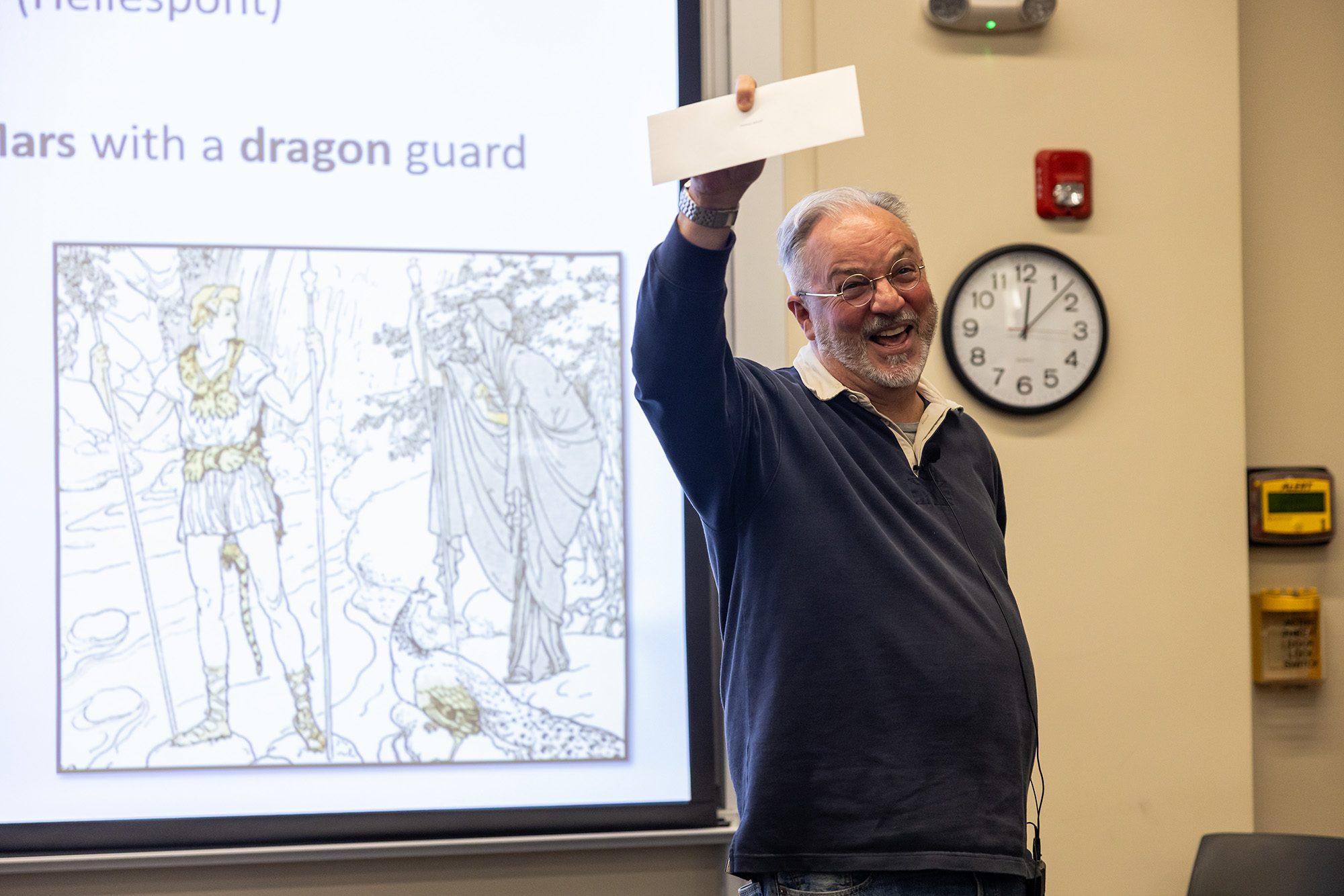 Professor at front of classroom holding up envelope