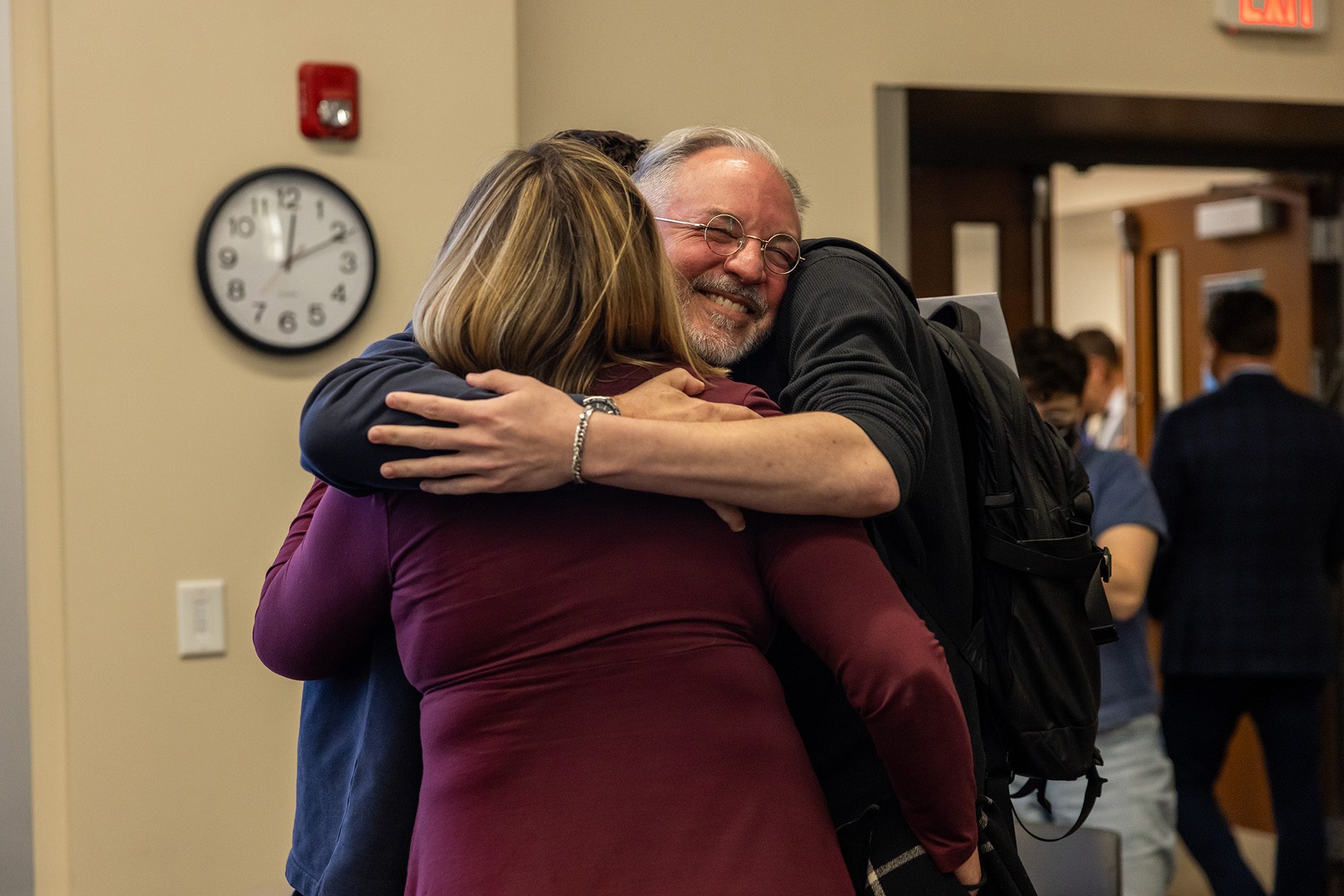 Professor hugging two people at the same time