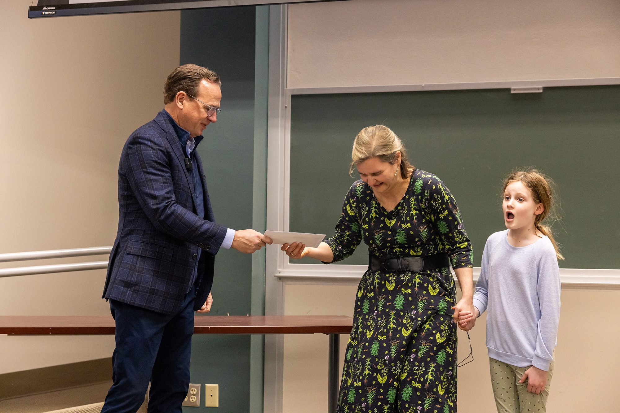 Professor being handed an envelope at the front of classroom