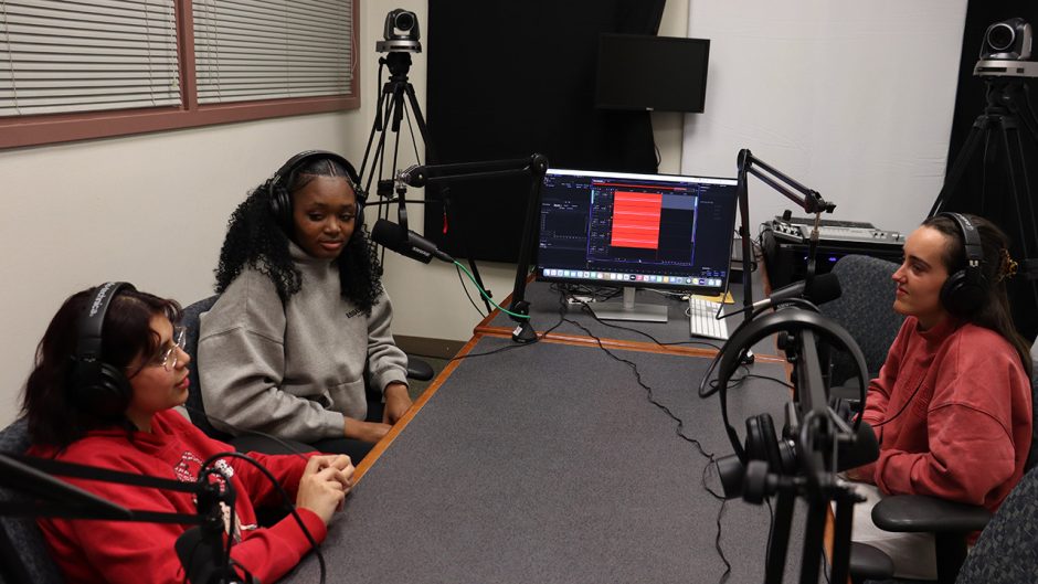 Three students use podcast room in Ellis Library digital lab.
