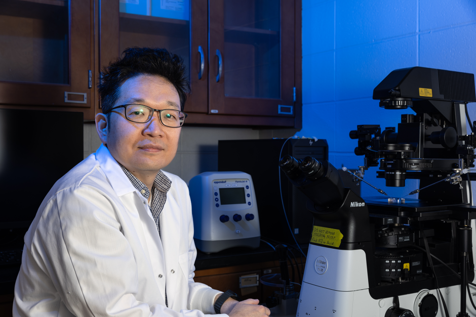 Kiho Lee posing in a lab with a microscope.