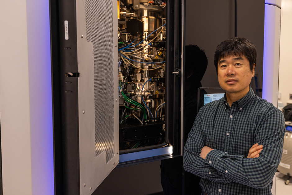 Min Su posing in front of lab equipment.