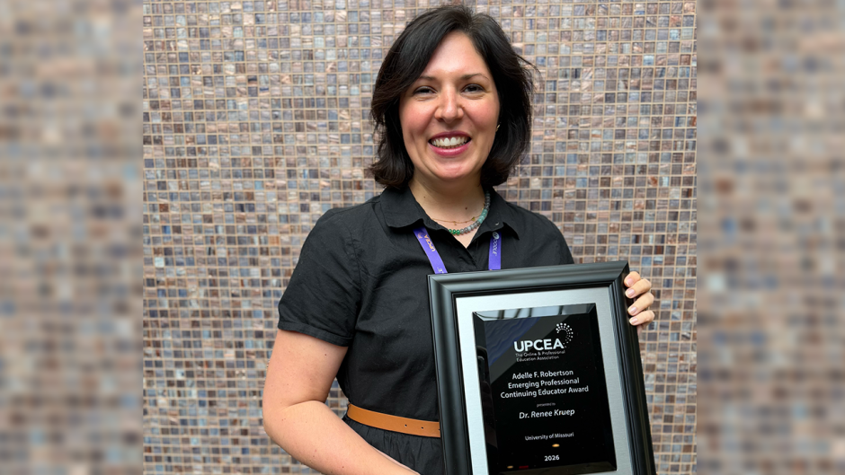 Renee Kruep holds an award from UPCEA