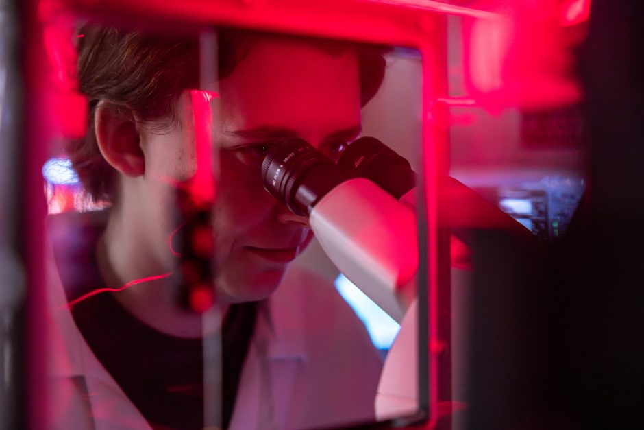 Researcher looking into a microscope