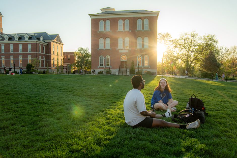 Students sitting on the grass in front of a building