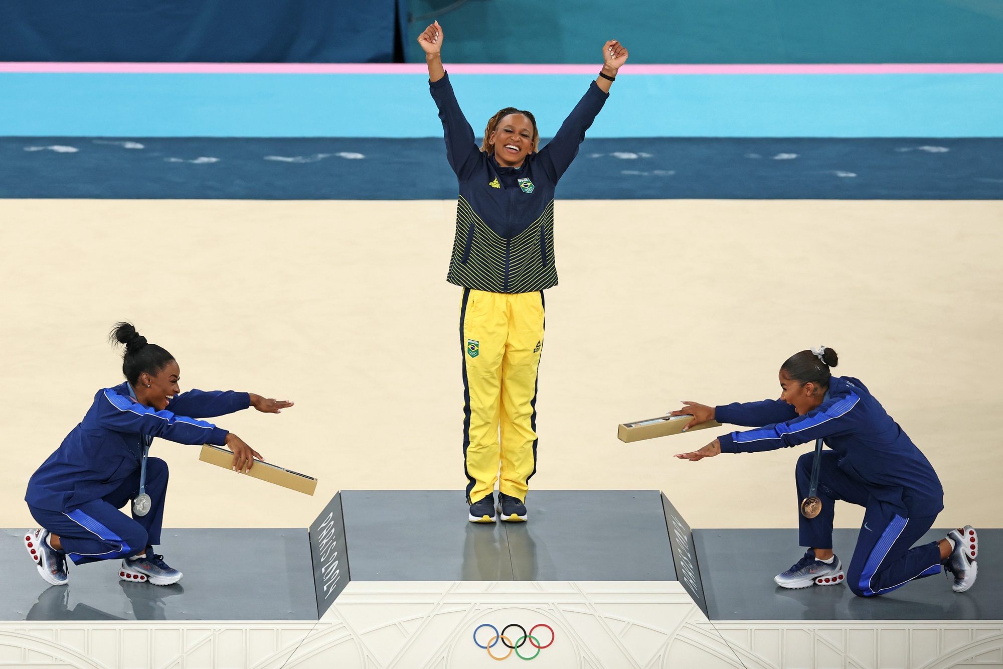 two olympic gymnasts bow to a third one on the medal podium