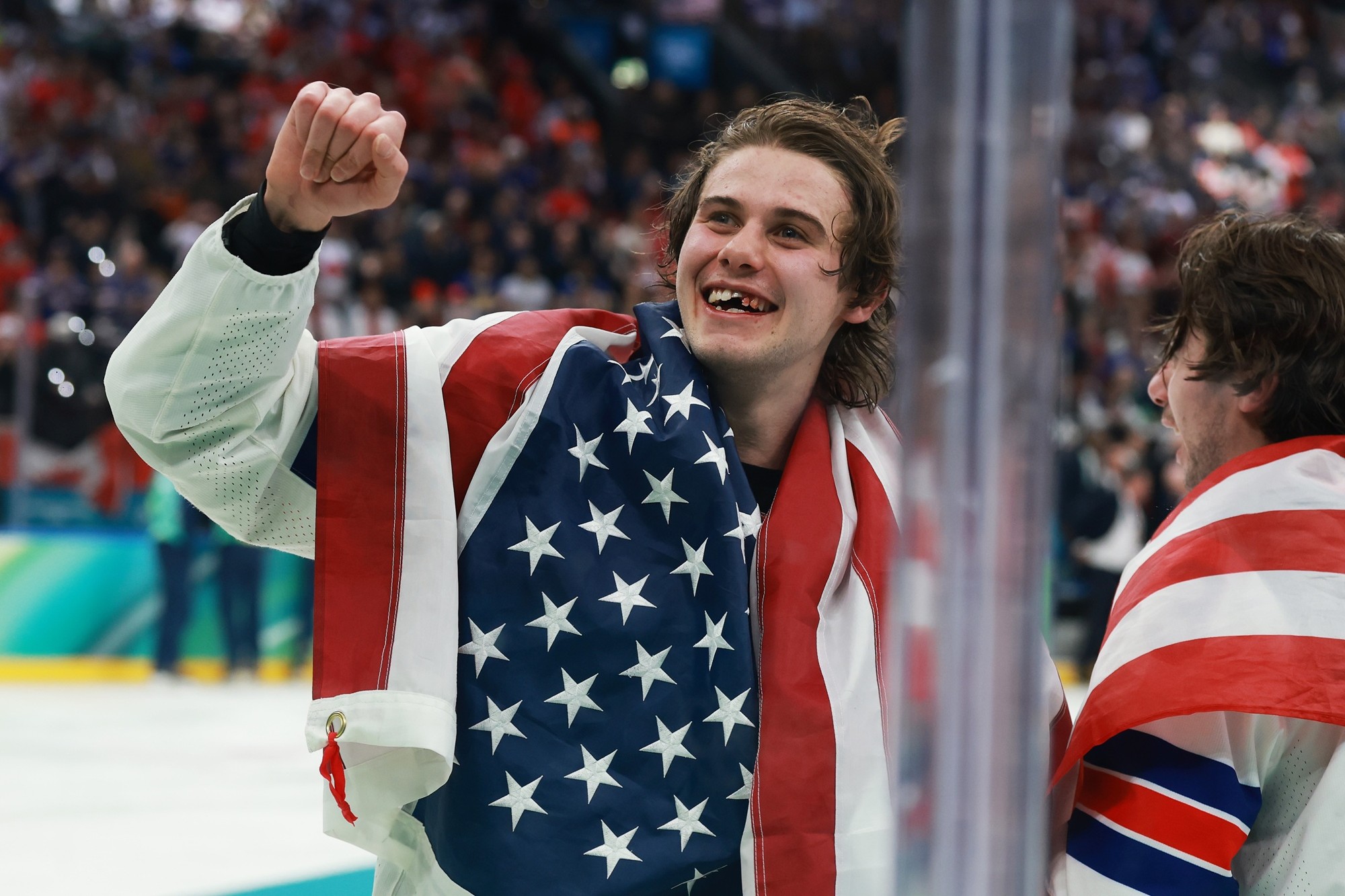 USA hockey player with raised fist and American flag draped over his shoulders