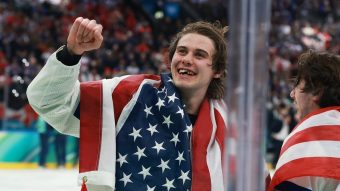 USA hockey player with raised fist and American flag draped over his shoulders