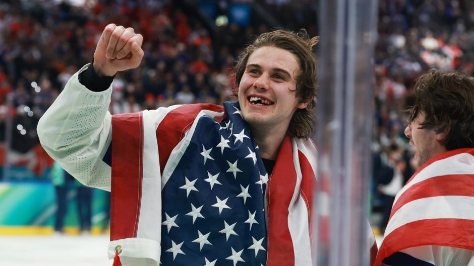 USA hockey player with raised fist and American flag draped over his shoulders