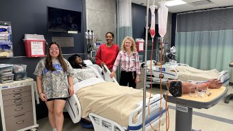 Three people in simulation lab at nursing school.