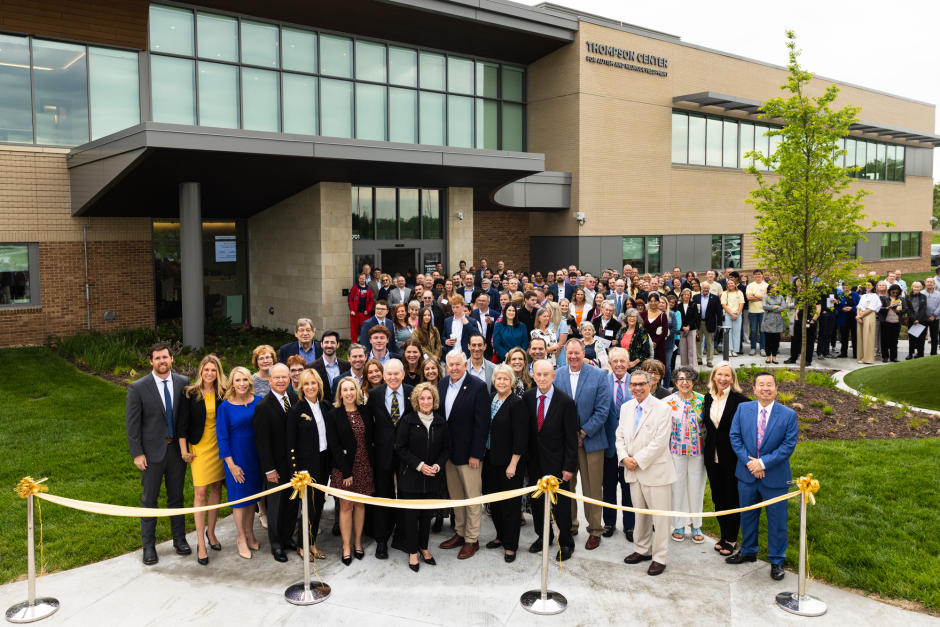 Large group stands behind ribbon