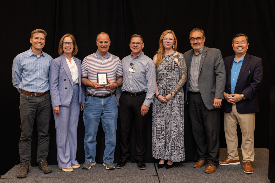 Jeff Liptak holds award with university leaders