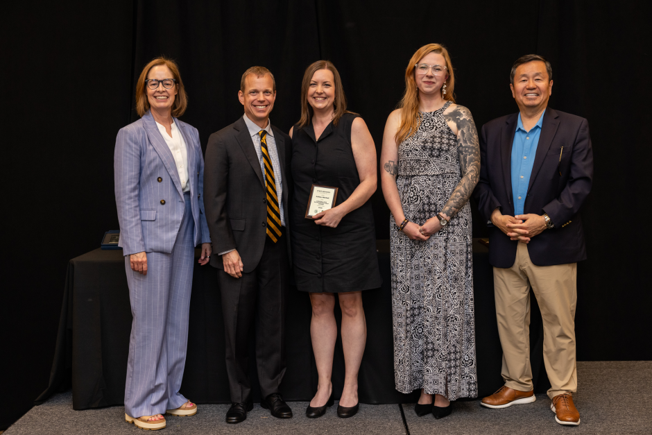 Ashley Mitchell holds award with university leadership