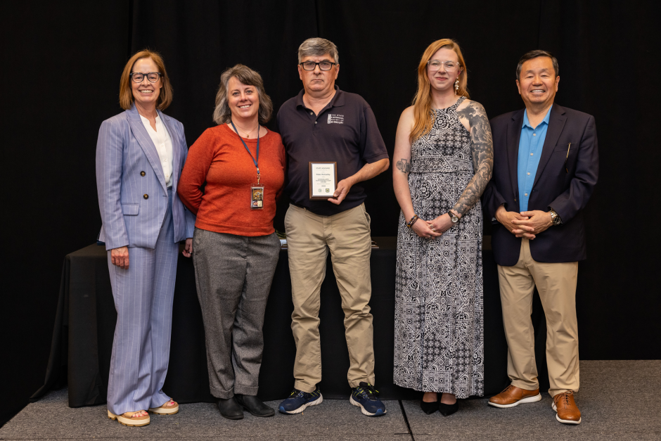 Peter McCarthy holds awards with university leaders