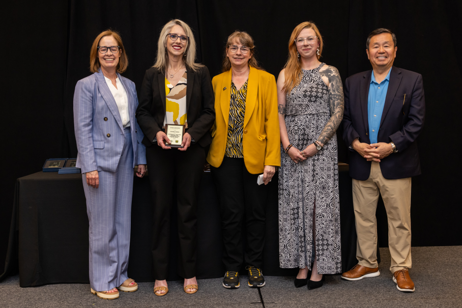 Marsha Fischer holds award with university leaders