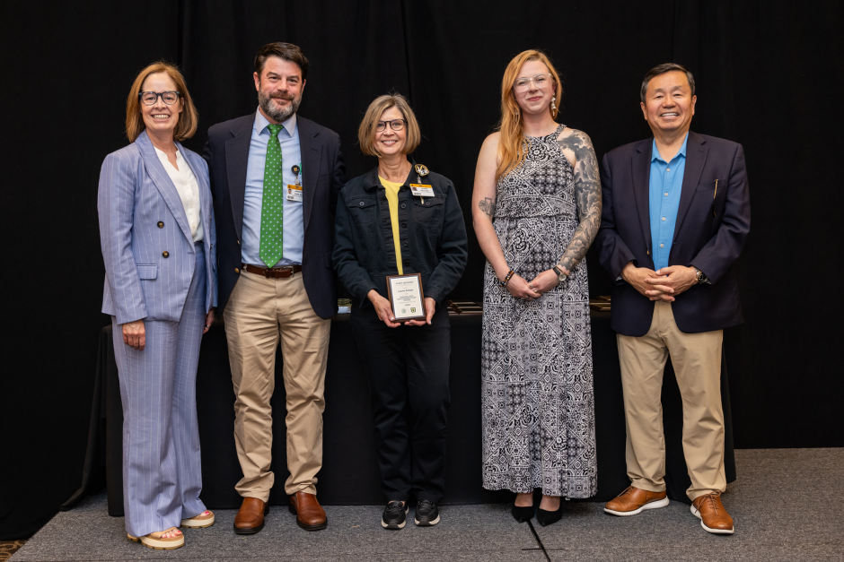 Laurie Pelster holds award with university leadership
