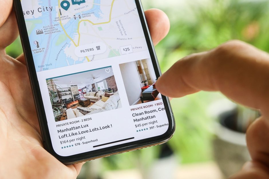 Woman's hand holding a phone while trying to book home apartment room in New York City