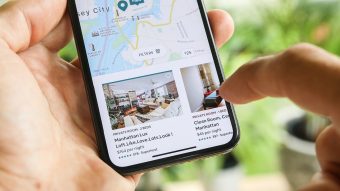 Woman's hand holding a phone while trying to book home apartment room in New York City