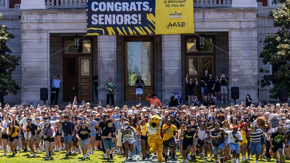 Truman the Tiger and many students beginning to run toward the Columns