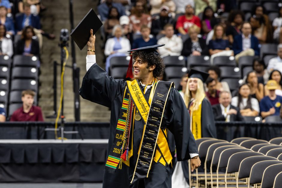 Graduate holding up diploma to the audience