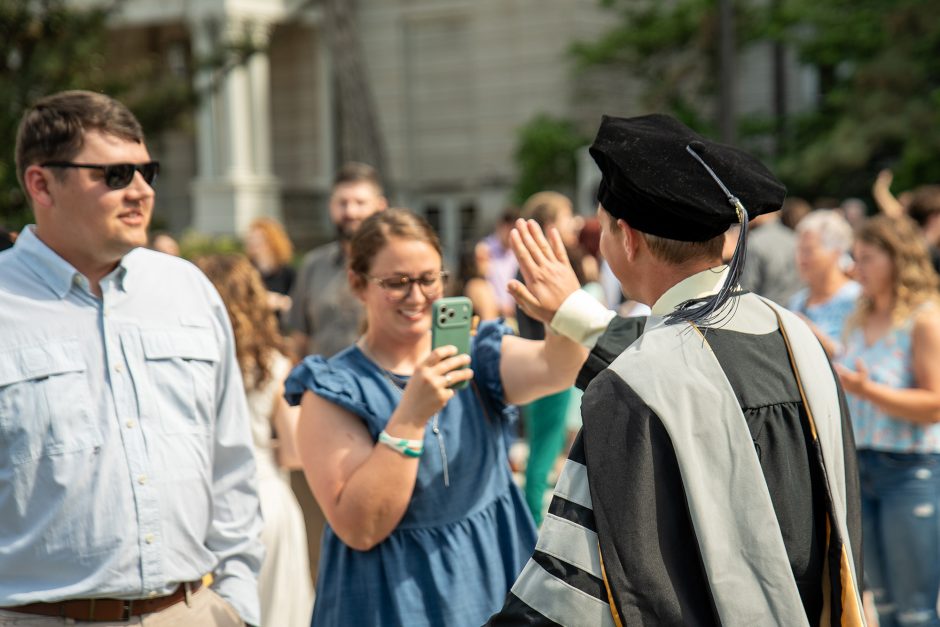 Graduate giving a high five to person taking the photograph