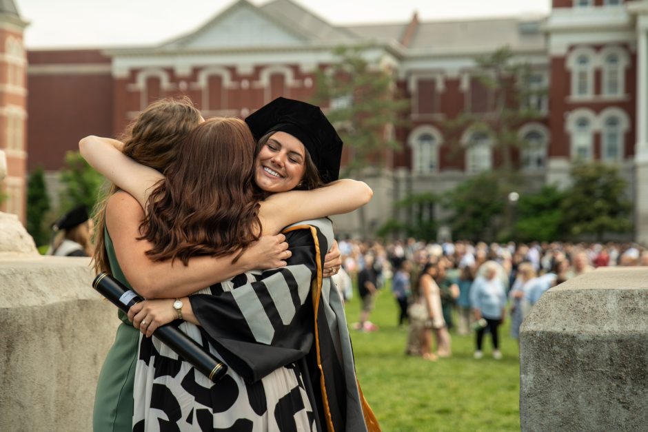 Graduate hugging others in between the Columns
