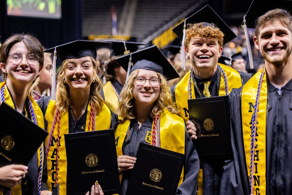 Group of five graduates with their diplomas