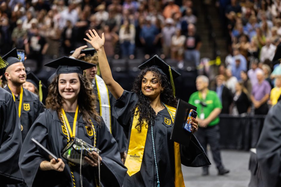 Graduate with arm raised to wave