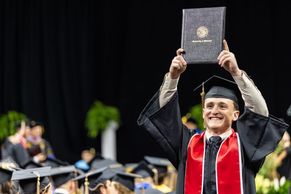 Graduate holding up diploma in celebration
