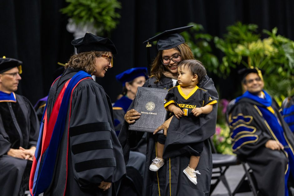 Graduate crossing the stage with child in arms