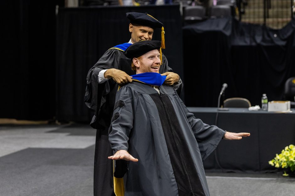 Graduate receiving a hood from a faculty member