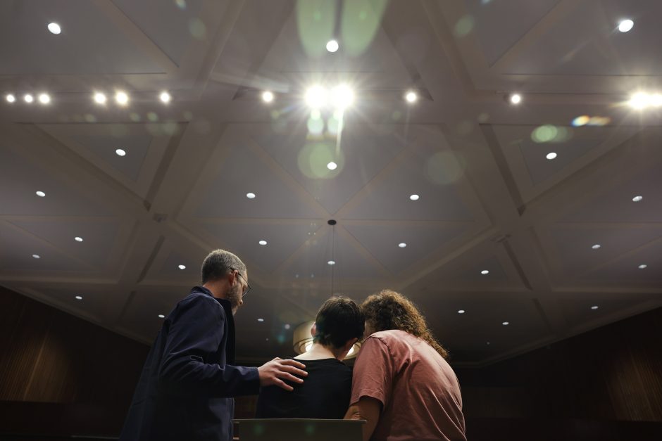 three people stand looking away from the camera