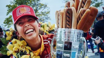 Camila Fowler celebrates in victory lane after the Wienie 500 with a wreath and a trophy with hot dogs sticking out of it