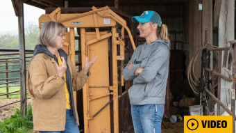 Two women in barn with video play button
