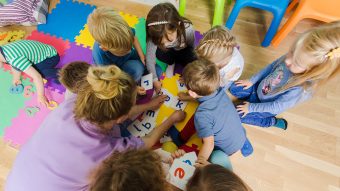 Childcare worker surrounded by children as they play with letters.