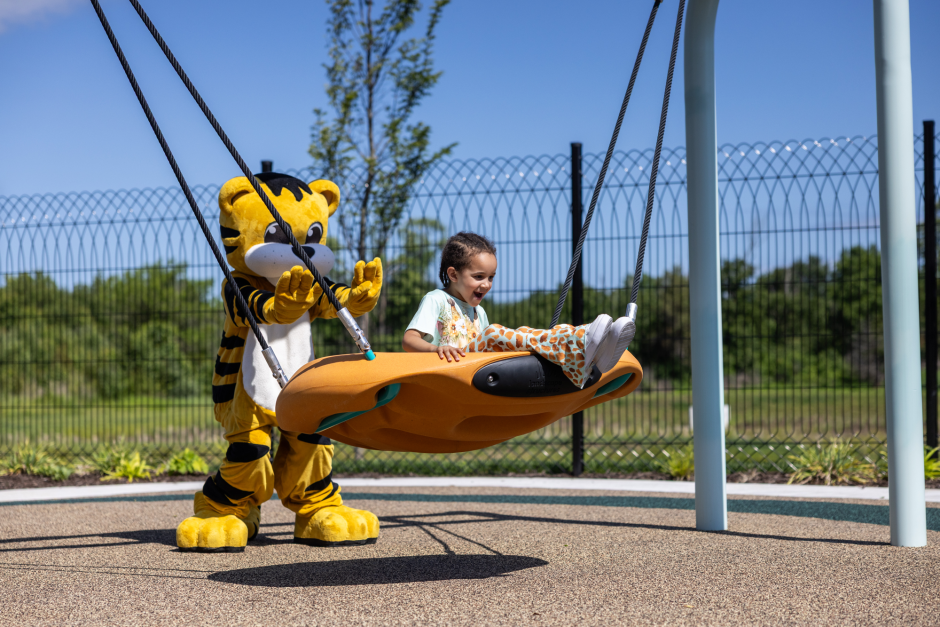TJ mascot with child on swing