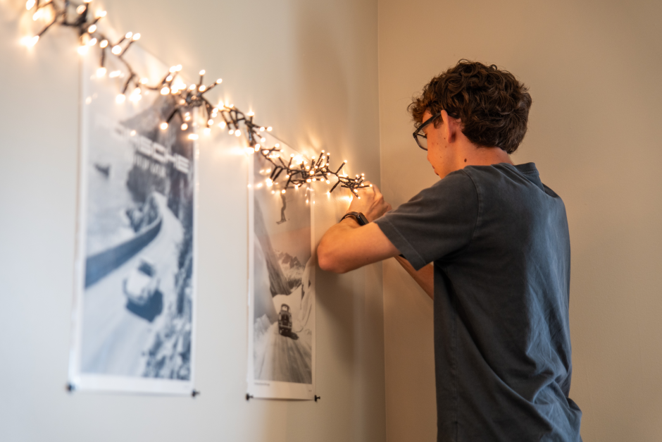 A student hangs lights on wall