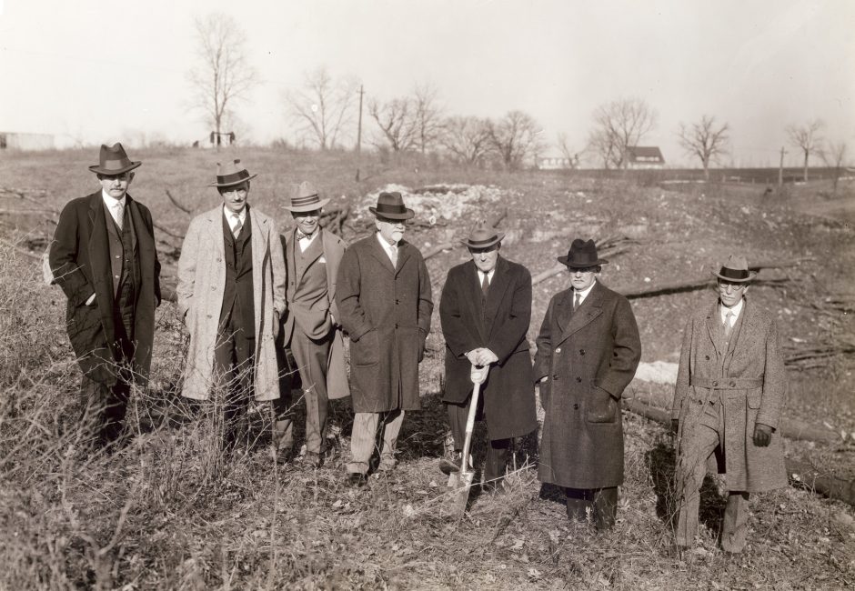 men in a barren field with shovels