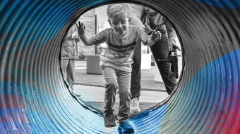 a boy walks through a playground tunnel