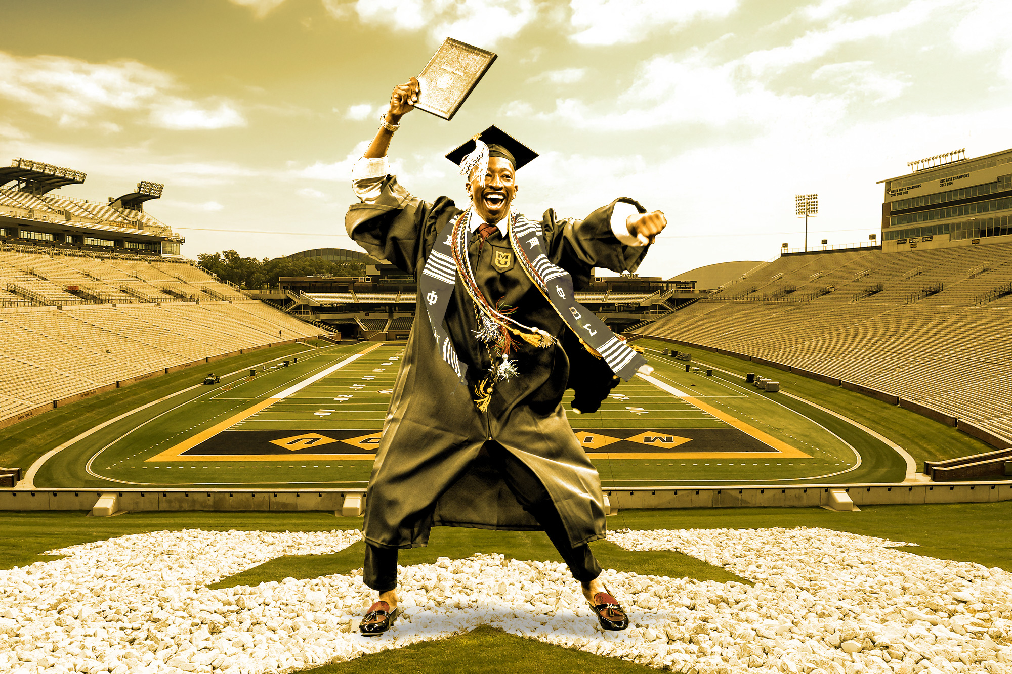 student waving diploma on the football field