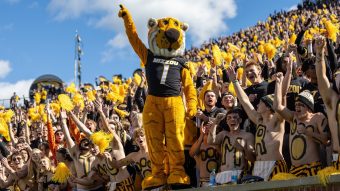 Truman the Tiger stands in front of students at a football game