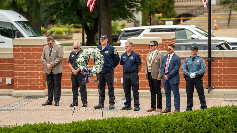Line of people standing behind a wreath on an easel