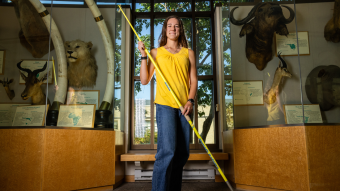Skylar Ciccolini holds her javelin while standing in front of a display of animal heads in the school of natural resources